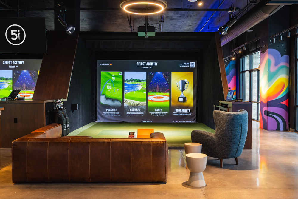 A simulator bay with a deep leather sofa and a mural along the far wall.